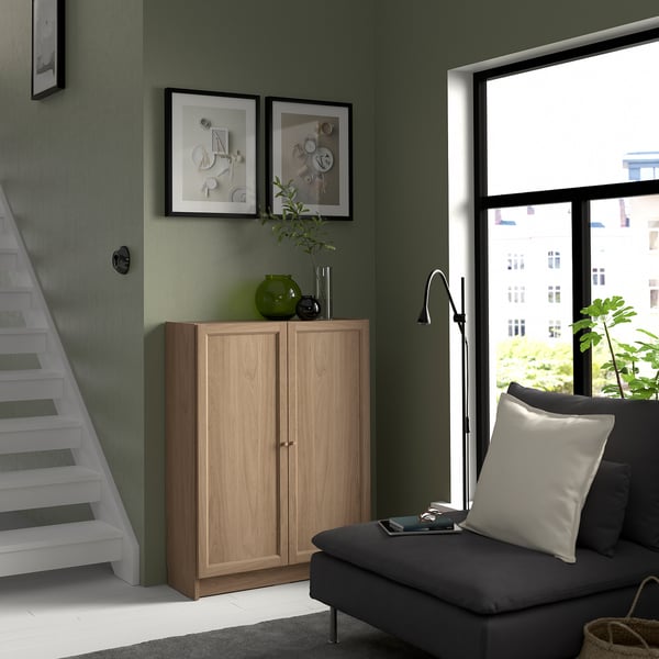 BILLY bookcase in light brown, green wall, dark grey sofa, decorative items, window view.
