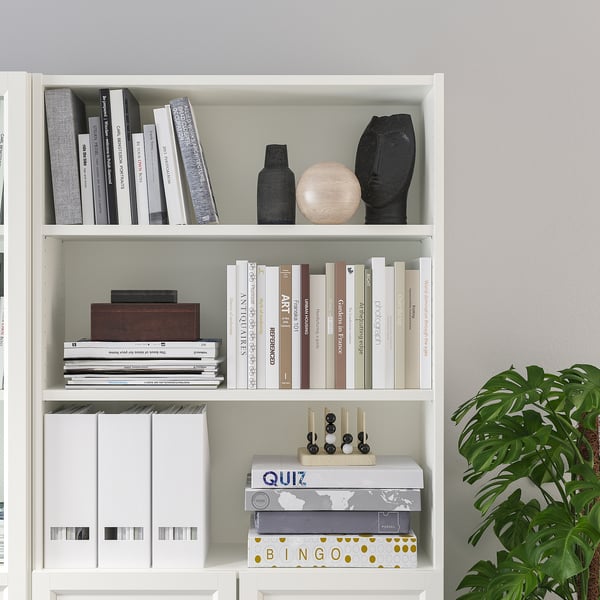 Bookshelf with adjustable shelves, displaying books, decorative items, and board games, organized neatly.