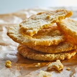 Stack of light brown, thin, crispy cookies on parchment.