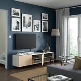 Modern living room: dark walls, wood tv stand, grey sofa, glass coffee table.