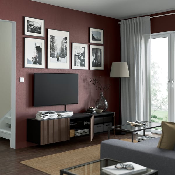 Modern living room with dark oak veneer cabinet, flat-screen tv, framed photos, lamp, and glass coffee table by window.