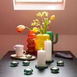 Colorful vases with flowers and candles, plus green glass BLADFÅGEL dishes.