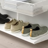 White shoe shelf, holding three pairs of mens shoes. -top shelf has a mesh basket.