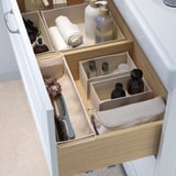 Organized drawer with divided soft boxes for toiletries, makeup, and brushes, utilizing space efficiently.