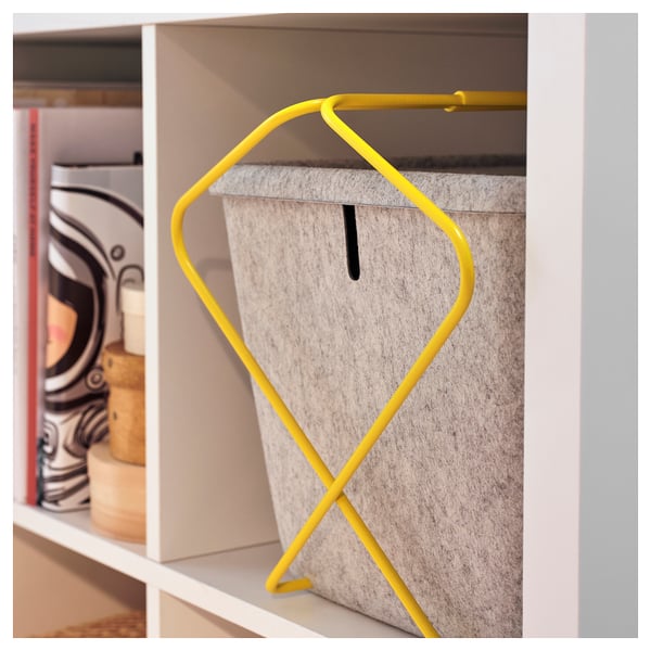 Bright yellow wire handle attached to light gray felt storage basket on white shelf, designed for easy carrying and charging of gaming accessories.