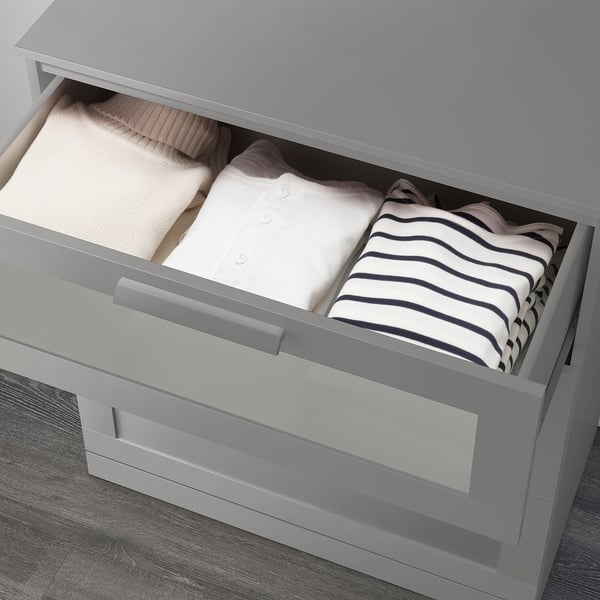 Open gray chest drawer revealing neatly folded clothes.