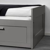 Grey day-bed with one drawer extended, neatly showing modern design and built-in storage.