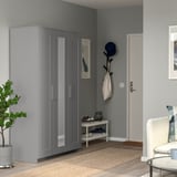 Modern entryway with gray BRIMNES wardrobe, shoe rack, and coat stand. Wardrobe mirrors the wall, adding depth. Decorated with plant and items.