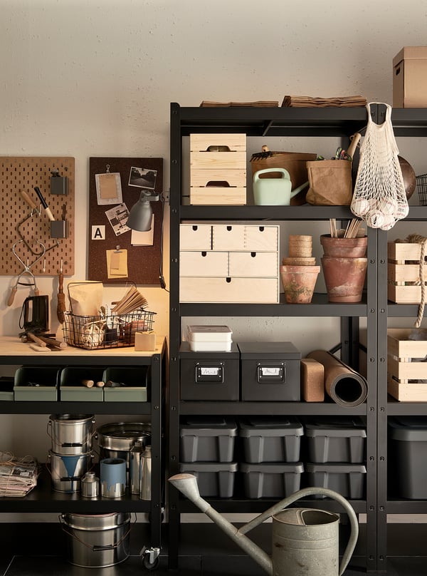 Black BROR storage shelves with metal containers, wooden boxes, gardening tools, and plant pots, organized neatly.