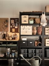 Black BROR storage shelves with metal containers, wooden boxes, gardening tools, and plant pots, organized neatly.