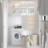 Clean laundry room: white washing machine, DIMPA beige sorting bags, open shelves with white items, gray towels.