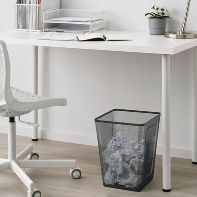 Minimalist office desk with chair, waste basket, and plants.