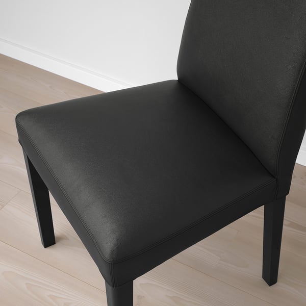 Black leather chair with wooden legs on wooden floor.
