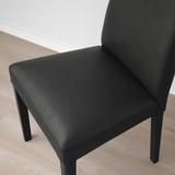 Black leather chair with wooden legs on wooden floor.