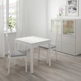 Small white dining set with square table and two cushioned chairs, ideal for cozy spaces.