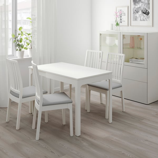 White dining set with extendable table and chairs, gray cushions, modern room.