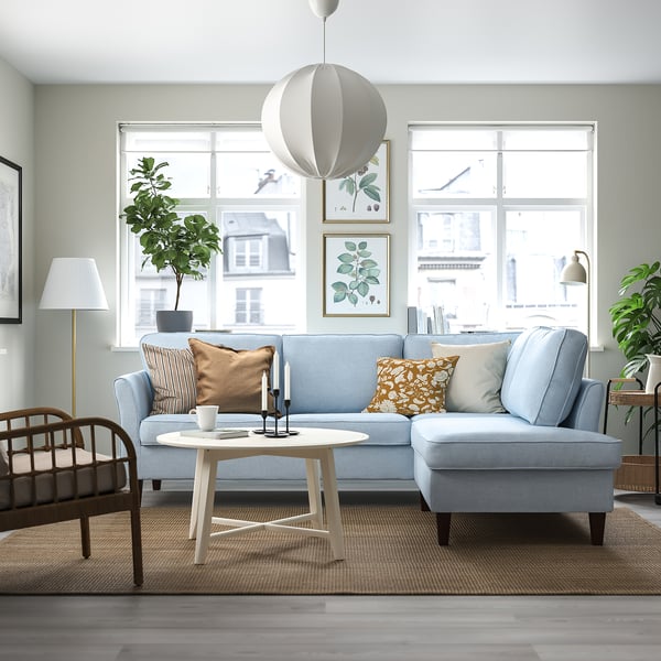 Modern living room with blue sofa, wood coffee table, large windows, rug, and plants.