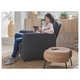 Person in EKOLSUND chair using tablet, headphones, casual attire.