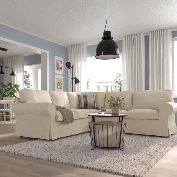 Beige EKTORP sectional, soft cushions. Modern living room with rug, wood floor, industrial lamp, plants.