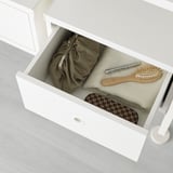 Open drawer with neatly folded clothes, a hairbrush, and small items. Ideal for organized storage in a bedroom.