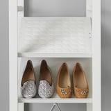 White closet with shoe shelf holding two pairs of shoes, one black and white, one brown with rhinestones, display for organized storage.