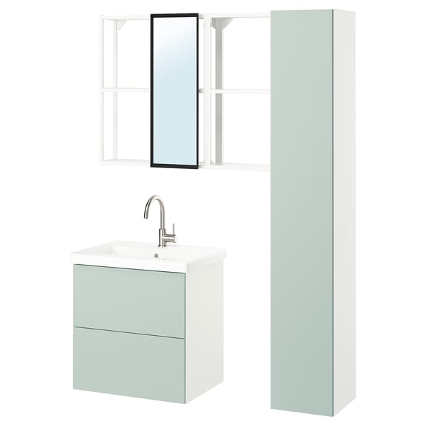 Modern bathroom setup: wall-mounted sink cabinet in pale green with two drawers, chrome faucet, tall cabinet, open shelves, and a framed mirror.
