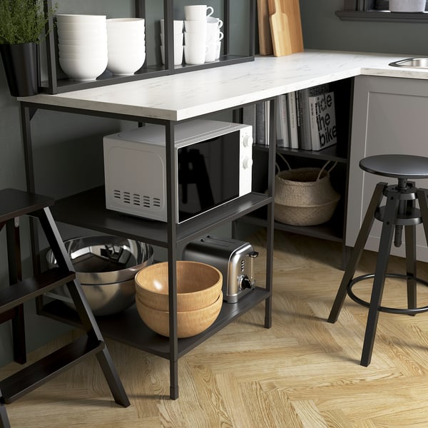 Modern kitchen island with microwave, toaster, bowls, and bar stools. Offers seating, storage, and workspace for cooking.