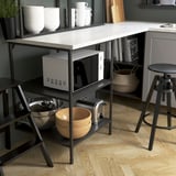 Modern kitchen island with microwave, toaster, bowls, and bar stools. Offers seating, storage, and workspace for cooking.