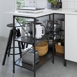 Kitchen island with open storage, appliances, and seating area.