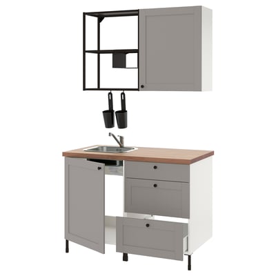 Modern compact kitchen in gray with wooden top, stainless sink, and hanging black utensils.