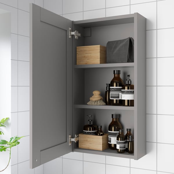 Open grey bathroom cabinet with mirror, storing toiletries andorganizers.