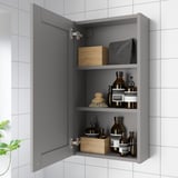 Open grey bathroom cabinet with mirror, storing toiletries andorganizers.