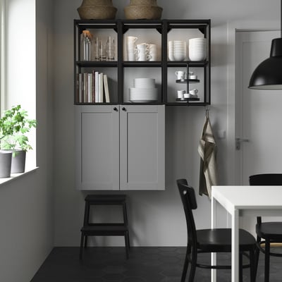 Grey ENHET kitchen with open shelves for dishes & bottles, black stool, & white dining table with black chairs.