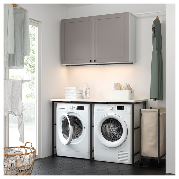 Modern laundry setup with ENHET grey cabinets and white appliances. Compact, efficient design with sorting, drying, and storage solutions.
