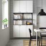 ENHET white storage unit with open/closed compartments, books, bowl, black chairs, pendant light.