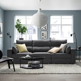 Modern living room with gray sofa, rug, and large windows. Spacious sofa with cushions and sleek coffee table.