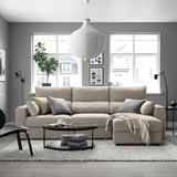 Modern living room with beige ESKILSTUNA sofa, coffee table, rug, plant, art, urban view.