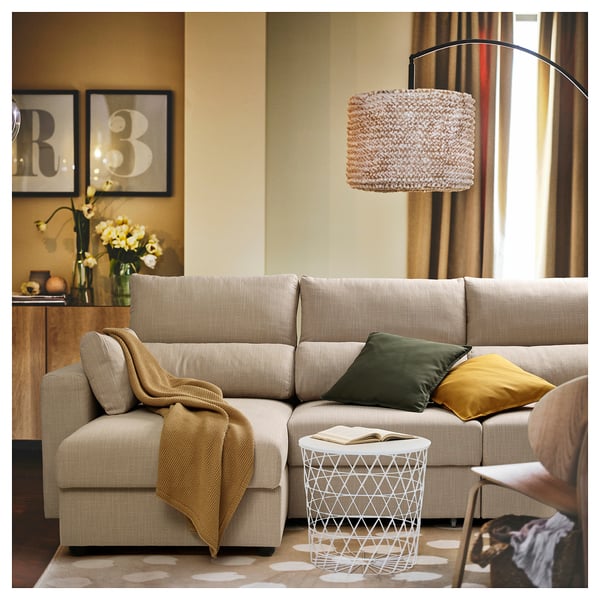 Beige ESKILSTUNA sectional with adjustable headrests, removable chaise, green & mustard pillows, under a pendant lamp.
