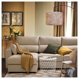Beige ESKILSTUNA sectional with adjustable headrests, removable chaise, green & mustard pillows, under a pendant lamp.