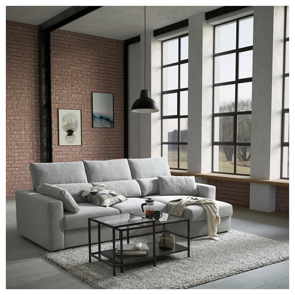 Modern living room with light gray ESKILSTUNA sofa, brick wall, large windows.