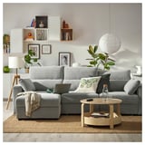 Modern grey fabric l-shaped sofa with adjustable cushions, wooden coffee table, and wall decor in a cozy living room.