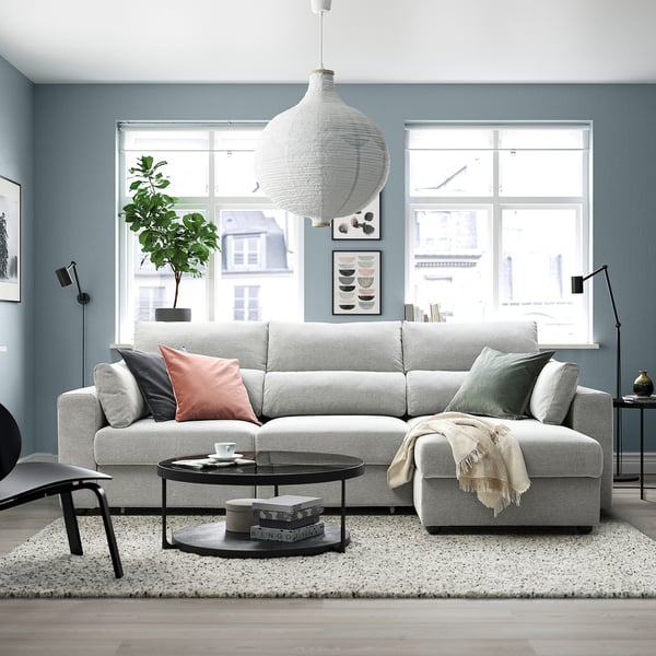 Grey ESKILSTUNA sectional sofa, plush cushions, high backrests, with coffee table and rug in modern living room.