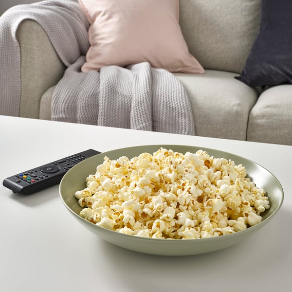 Bowl of popcorn and tv remote on a coffee table, suggesting a relaxed movie night at home.