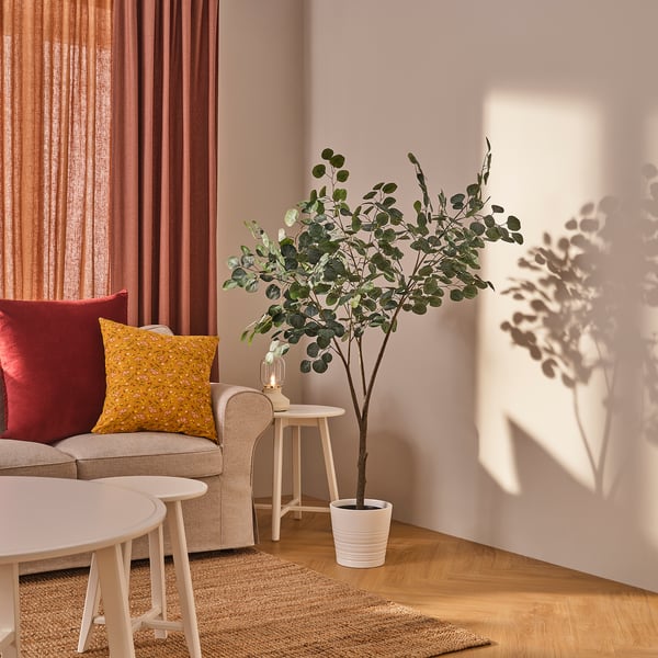 Living room with red curtains, beige sofa, and plant.