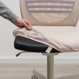 Hand pulling light pink FLINTAN chairs seat cover, revealing black underneath. Mesh backrest visible.