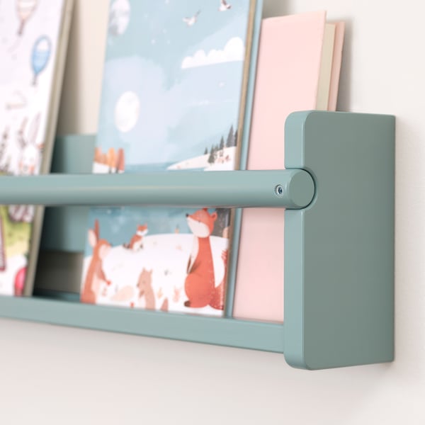 A neatly designed green wooden wall shelf holding books and framed pictures.