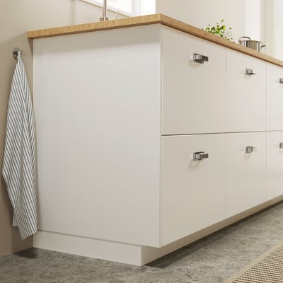 White kitchen cabinets with silver handles and striped dish towel.