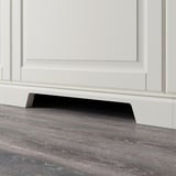 Black plinth with cut-out for ventilation under white cabinet.