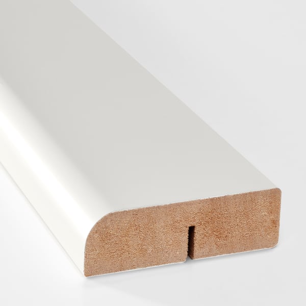 Close-up of modern kitchen trim, rounded edge, light wood finish.