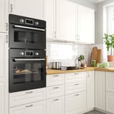 Black FORNEBY double oven in white kitchen with digital controls.